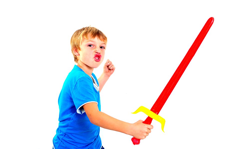 Young boy in studio playing with sword on white background